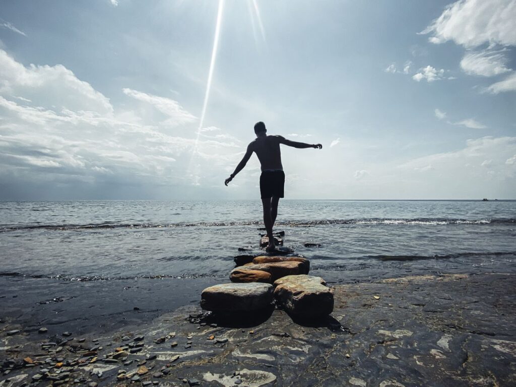 pexels-photo-12995815 Silhouette of a man balancing on rocks by the sea at sunset, Sputnik, Russia.